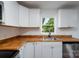 Cozy kitchen featuring white cabinets, butcher block countertops, and stainless steel sink at 1411 Caldwell St, Gastonia, NC 28052