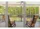 Inviting screened-in porch with rocking chairs overlooking the backyard forest at 1956 Forest Ridge Dr, Stanley, NC 28164