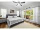 Light-filled bedroom boasts a comfortable bed, wood floors, and large windows with a view of the deck at 1956 Forest Ridge Dr, Stanley, NC 28164