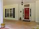 A welcoming covered front porch with red front door and tasteful decor at 1956 Forest Ridge Dr, Stanley, NC 28164