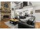 Open-concept living room with stone fireplace, dark leather sectional sofa, and access to kitchen at 1956 Forest Ridge Dr, Stanley, NC 28164