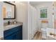 Well-lit bathroom featuring modern vanity, stylish mirror, and shower with white ruffled curtain at 281 Emerald Shores Rd, Mount Gilead, NC 27306