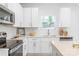 Bright kitchen features white cabinets, stainless steel appliances, stone countertops and backsplash, and light wood flooring at 2813 New Pineola Rd, Charlotte, NC 28208