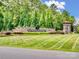 Community entrance sign featuring a stone base, manicured lawn, and lush landscaping at 3103 Oliver Stanley Trl, Lancaster, SC 29720