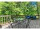 Back deck, surrounded by lush greenery, boasts an outdoor dining set and a comfortable seating area at 335 Bob White Run, Salisbury, NC 28147