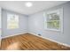 This empty bedroom features hardwood floors, two windows, and neutral walls at 3828 Delgany Dr, Charlotte, NC 28215