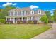 Inviting two-story home featuring a manicured lawn, brick accents, covered front porch, and mature landscaping at 3864 Meadow Ridge Nw Dr, Concord, NC 28027