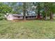 Spacious backyard with mature trees surrounding a cozy home featuring a brick chimney at 402 School St, Rockwell, NC 28138