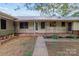 Charming single-story home with a metal roof, cozy front porch, and neatly landscaped garden beds at 402 School St, Rockwell, NC 28138