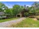 A charming barn with an open shelter sits on a gravel driveway surrounded by grass and trees at 4038 Forest Brook Dr, Edgemoor, SC 29712
