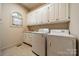 Well-lit laundry room with white cabinets, countertops, sink, washer, dryer, and a window at 4509 Rosecliff Dr, Charlotte, NC 28277