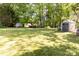 Spacious backyard featuring a large lawn, mature trees, and storage sheds at 5014 Oxford School Rd, Claremont, NC 28610