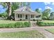 Quaint single-story home with a covered front porch, dormer window, mature trees, and lush landscaping at 531 Walnut St, Statesville, NC 28677