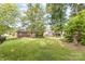 View of the grassy backyard with mature trees and landscaping at 5706 Sustar Dr, Monroe, NC 28110
