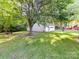 Backyard view featuring a detached garage nestled among mature trees and lush green grass at 70 Cumberland Sw Ct, Concord, NC 28025