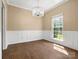Well-lit dining room with hardwood floors, wainscoting, an elegant chandelier, and a large window at 9430 Peckham Rye Rd, Mint Hill, NC 28227