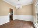 Elegant dining room with hardwood floors, wainscoting, stylish chandelier, and a view into the kitchen at 9430 Peckham Rye Rd, Mint Hill, NC 28227