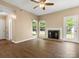Cozy living room with ceiling fan, fireplace, hardwood floors, and backyard view through bright windows at 9430 Peckham Rye Rd, Mint Hill, NC 28227