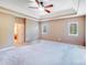 Expansive bedroom with neutral carpet, tray ceiling, ceiling fan, and abundant natural light from two windows at 9433 Stonebridge Way, Mint Hill, NC 28227