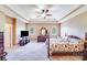 Spacious bedroom features a tray ceiling, ceiling fan, and carpeted floor, alongside a dresser and TV console at 9433 Stonebridge Way, Mint Hill, NC 28227