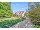 Charming brick home with mature trees and a long driveway on a sunny day at 9433 Stonebridge Way, Mint Hill, NC 28227