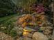 A charming rock waterfall with lush greenery adds a touch of nature to the landscape at 9433 Stonebridge Way, Mint Hill, NC 28227