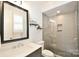 Modern bathroom with a glass shower, gray tile, and a black framed mirror at 9596 Pacing Nw Ln, Concord, NC 28027