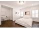 Bright bedroom featuring white walls, hardwood floors, plantation shutters, and a stylish crystal light fixture at 9596 Pacing Nw Ln, Concord, NC 28027