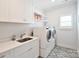 Bright laundry room featuring white cabinets, modern machines, and a designer floor at 9596 Pacing Nw Ln, Concord, NC 28027