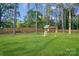 Lush backyard featuring a wooden playground, a fire pit, and ample green space at 10125 Bethel Church Rd, Midland, NC 28107