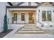 Inviting entryway with stone facade, brick steps, wood door, and modern lighting fixtures under a covered porch at 10125 Bethel Church Rd, Midland, NC 28107