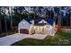 A beautifully lit home at dusk featuring board and batten siding, dark roof, and well-manicured landscape at 10125 Bethel Church Rd, Midland, NC 28107