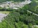 An aerial view showcases the property's location with mature trees, a road nearby, and retail establishments in the distance at 1029 Sullivan St, Wadesboro, NC 28170