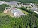 An aerial view reveals an industrial building surrounded by a parking area and mature trees near a busy highway at 1029 Sullivan St, Wadesboro, NC 28170