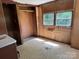 A view of the bedroom showcasing the closet space, worn floors, wood paneled walls, and natural light at 1029 Sullivan St, Wadesboro, NC 28170