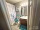 Well-lit bathroom featuring tile floors, a single sink vanity, and a tub with a white and blue decorative shower curtain at 10804 Back Ridge Rd, Charlotte, NC 28277