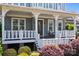 Inviting front porch with classic white railings, comfortable seating, and lush, colorful landscaping at 10822 Brandie Meadow Ln, Huntersville, NC 28078