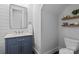 Stylish powder room with blue vanity, modern mirror, and wood floating shelves at 10822 Brandie Meadow Ln, Huntersville, NC 28078