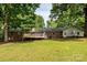 The back exterior view showcases a brick ranch-style home with a deck and expansive green lawn at 13030 Mayes Rd, Huntersville, NC 28078