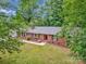 Charming brick home features black shutters, a well-manicured lawn, and a welcoming walkway, all framed by mature trees at 13030 Mayes Rd, Huntersville, NC 28078