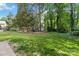 Picture of a spacious, shady backyard with mature trees, a fire pit, and a storage shed at 1308 Pennington Nw Pl, Concord, NC 28027
