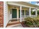 Inviting front porch with brick accents, green door and manicured landscaping at 1308 Pennington Nw Pl, Concord, NC 28027