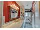 Bathroom featuring red walls, a large mirror, and a white marble countertop sink with a shower and toilet at 211 Amos Homesley Rd, Cherryville, NC 28021
