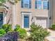 A townhome showing the entryway with blue door, garage and landscaped shrubbery at 2125 Belle Vernon Ave, Charlotte, NC 28210