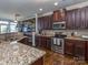 Kitchen with granite countertops, dark wood cabinetry, stainless steel appliances, and mosaic backsplash at 2125 Belle Vernon Ave, Charlotte, NC 28210
