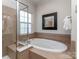 Indulge in this pristine bathroom with soaking tub, separate glass shower, and neutral tile surround at 2125 Belle Vernon Ave, Charlotte, NC 28210