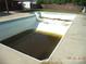 Empty inground pool showing signs of needed repair, presenting a renovation opportunity for summer fun at 216 N Rowan Ave, Spencer, NC 28159