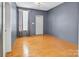 An empty room with hardwood floors, blue walls, a window with a gray curtain, and a white door at 226 Magnolia Ave, Charlotte, NC 28203