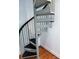 View of a compact gray spiral staircase with black stair treads and wooden floors near the bottom of the stairs at 226 Magnolia Ave, Charlotte, NC 28203