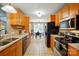 Well-lit kitchen with wood cabinets, black appliances, and a view of the dining area at 2745 Stockwood Dr, Gastonia, NC 28056
